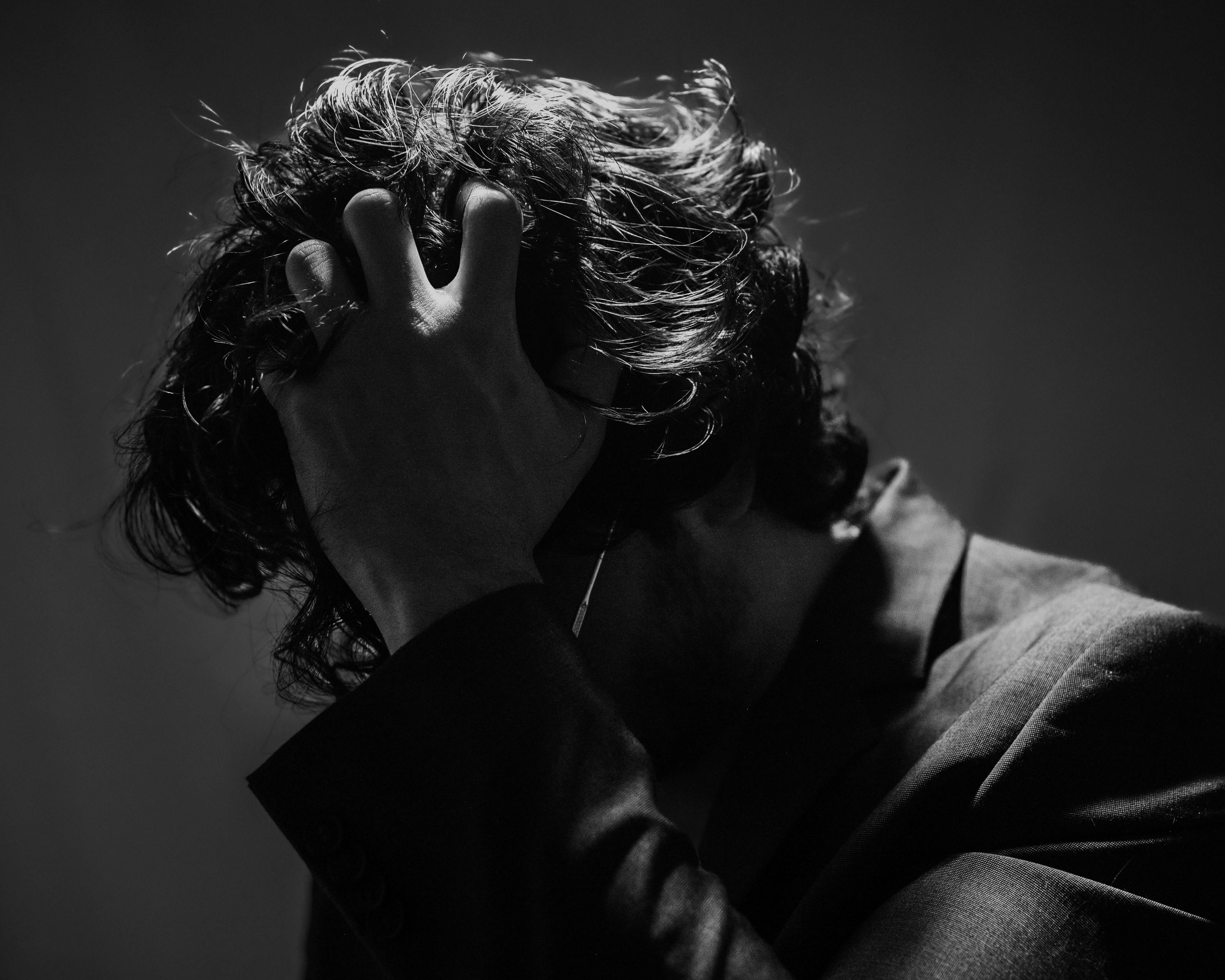 A man scratching his head, looking overwhelmed and mentally exhausted.